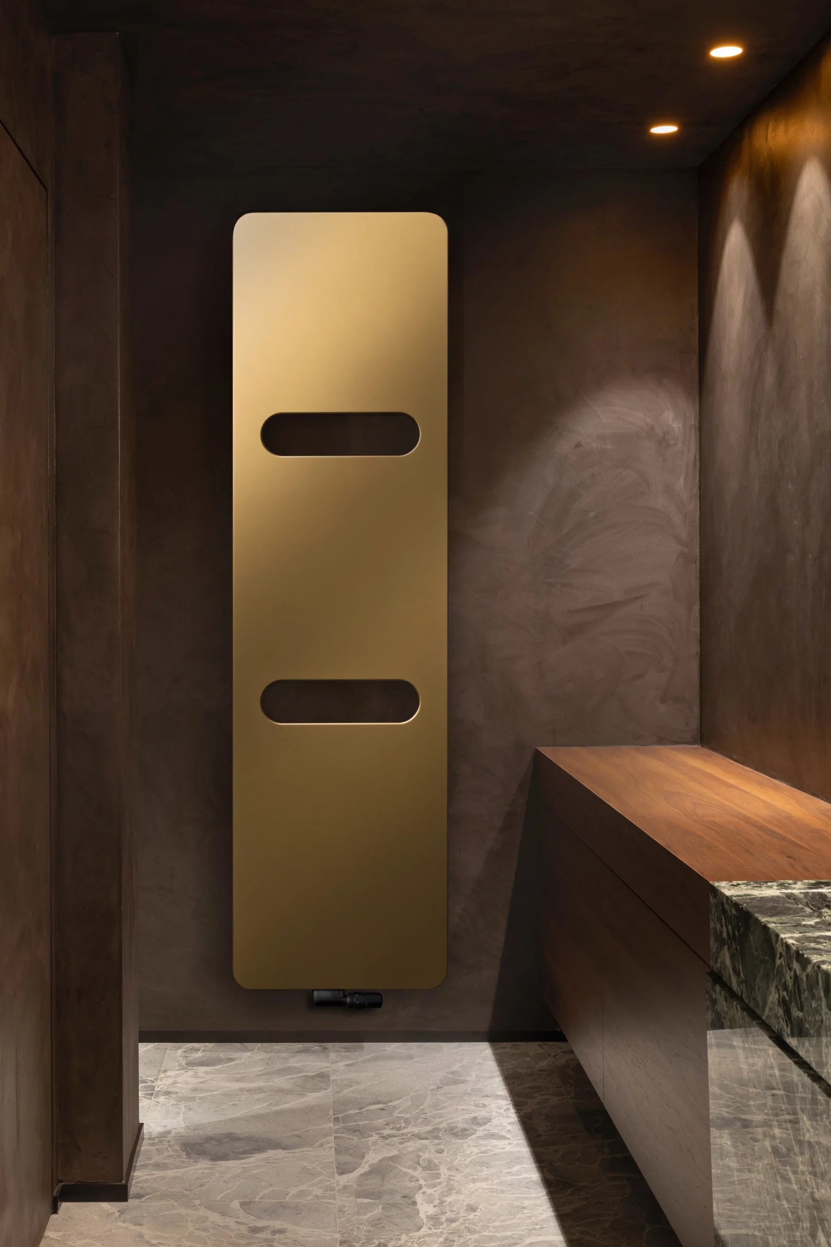 Elegantes Bad mit goldenem Heizkörper und Marmor. Salle de bain élégante avec radiateur doré et marbre.